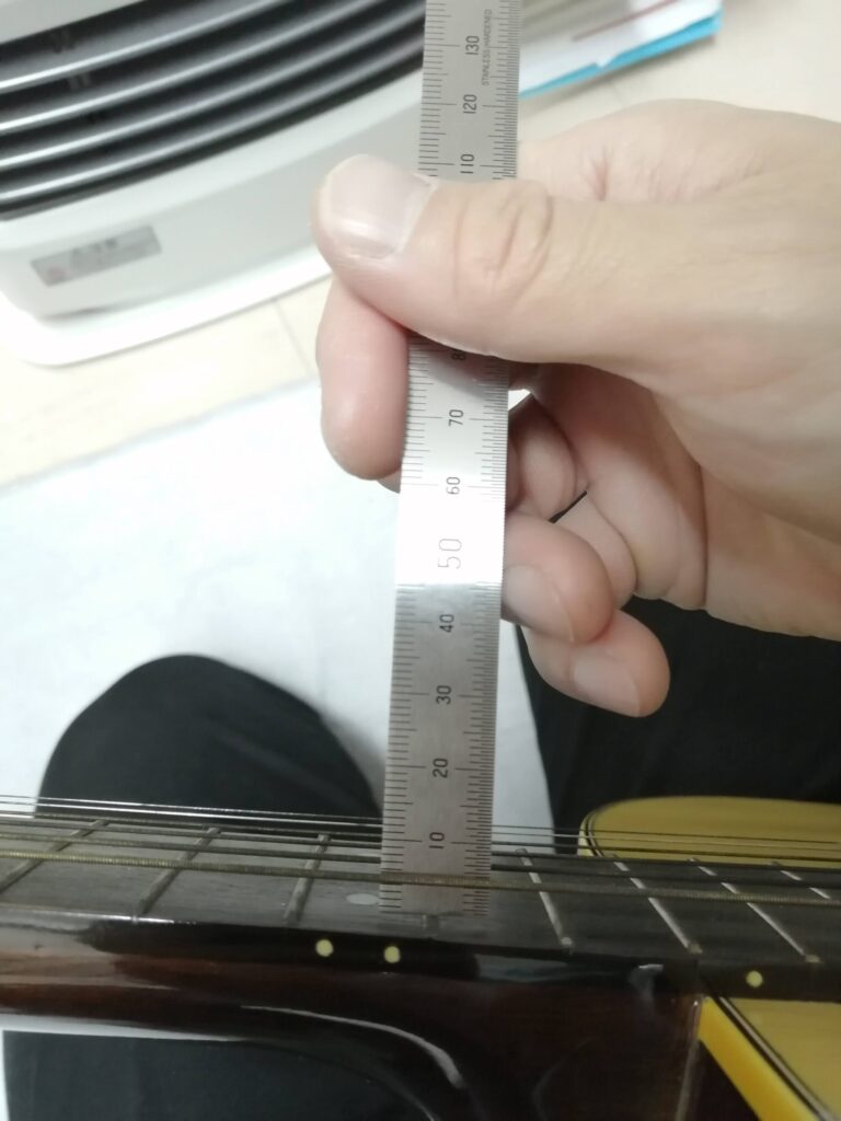 定規でギターの弦高を測っているところ